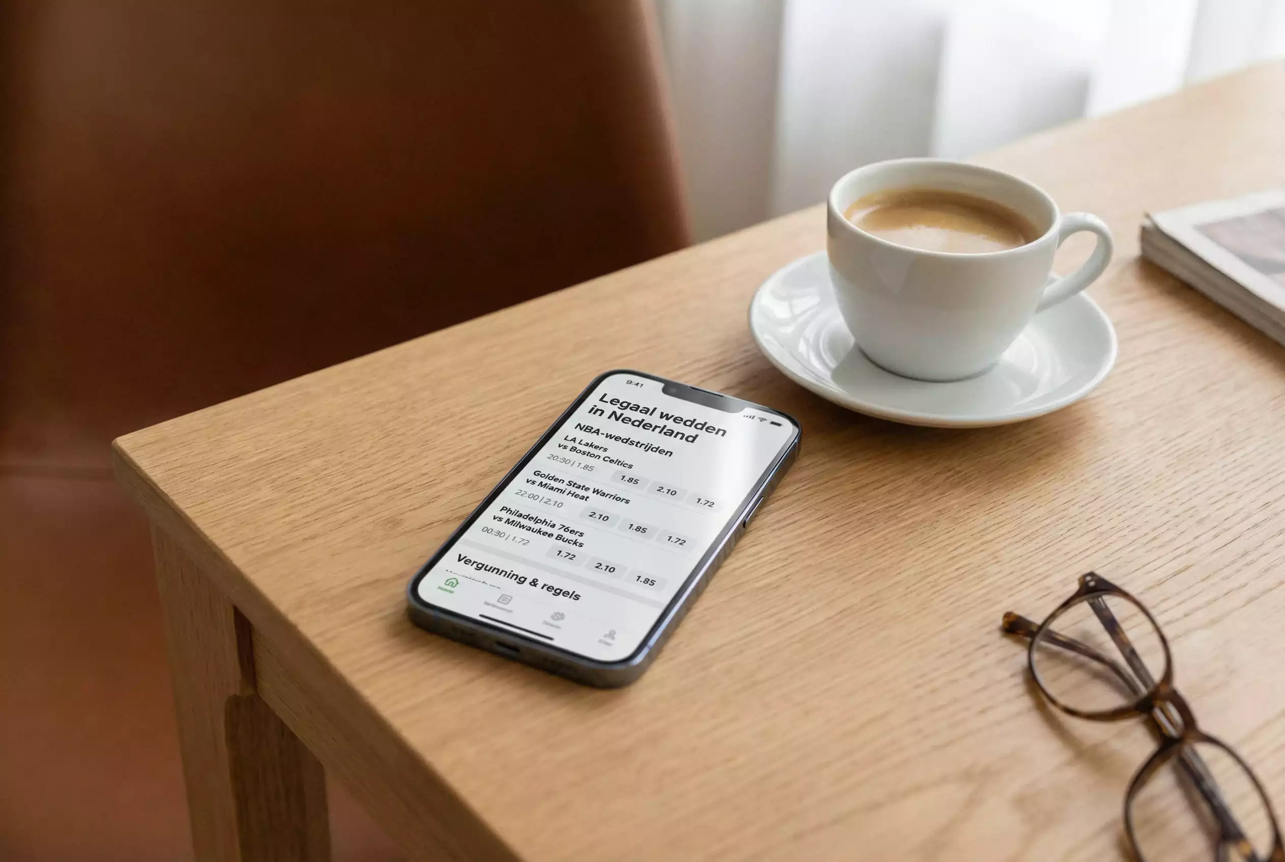 Smartphone met NBA-weddenschap-interface op een bureau naast een kop koffie